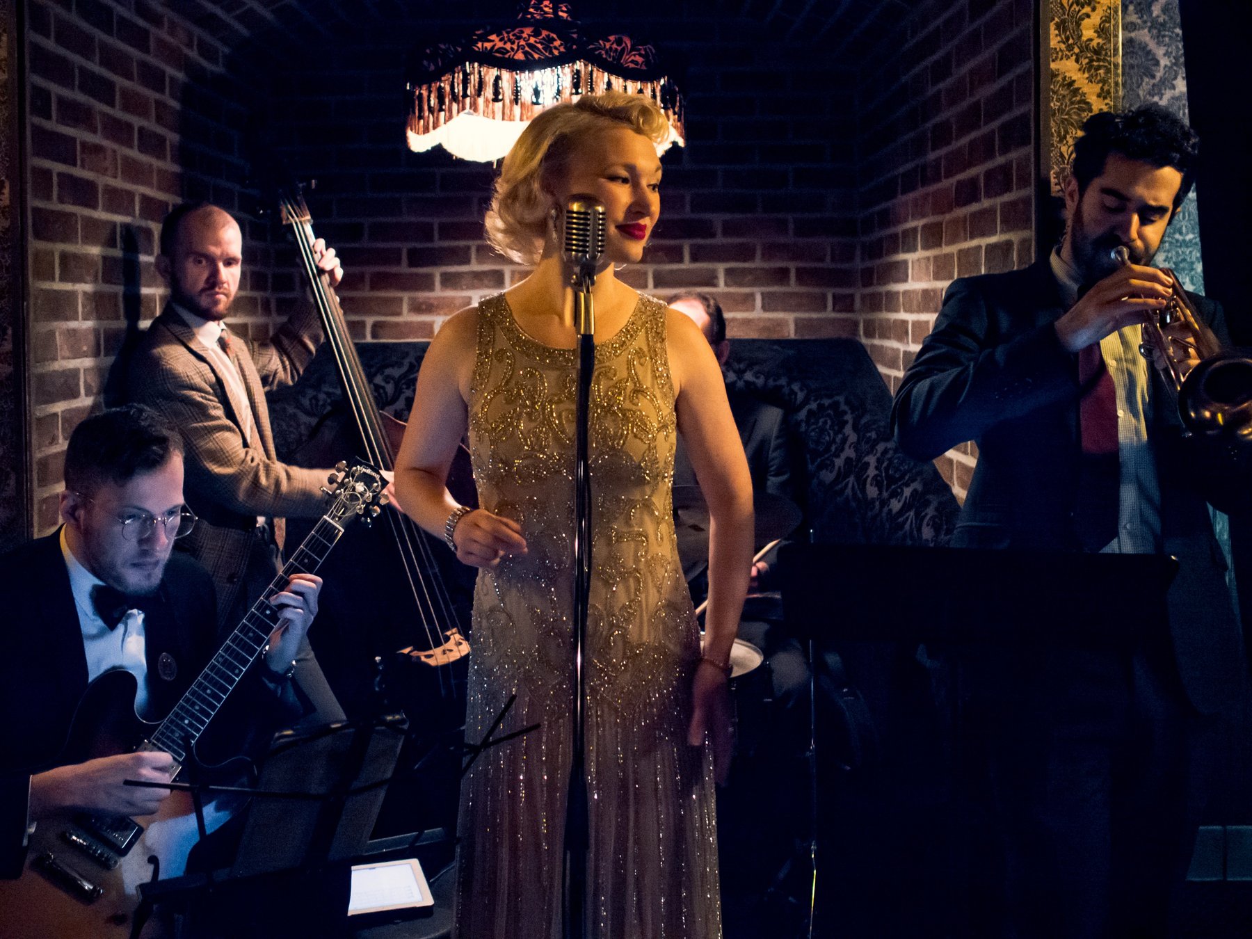 Musicians performing in a dim brick room beneath a decorative dragon.