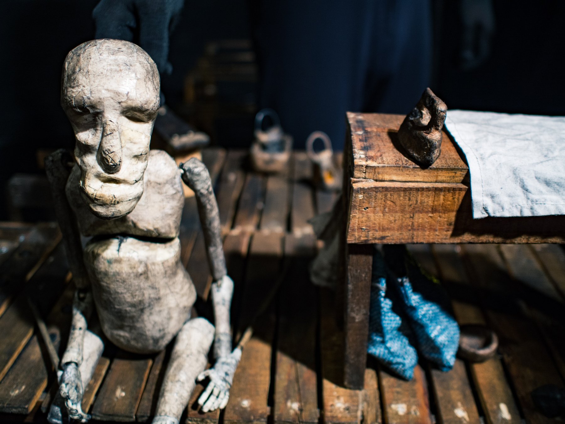 A carved wooden figure in a dim workshop, lit by a shaft of sunlight.